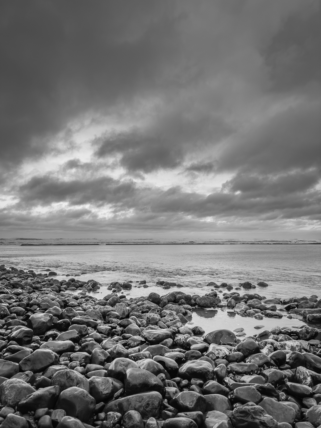 A black and white photo of rocks on a beach.